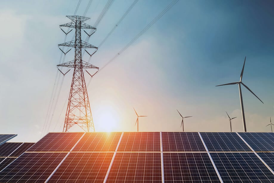 Strommast mit Solarmodulen und Windenergieanlagen im Gegenlicht