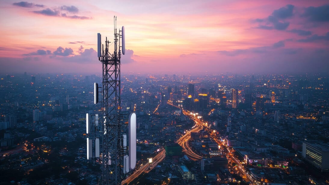 Mobilfunkmast über einer abendlichen Stadt